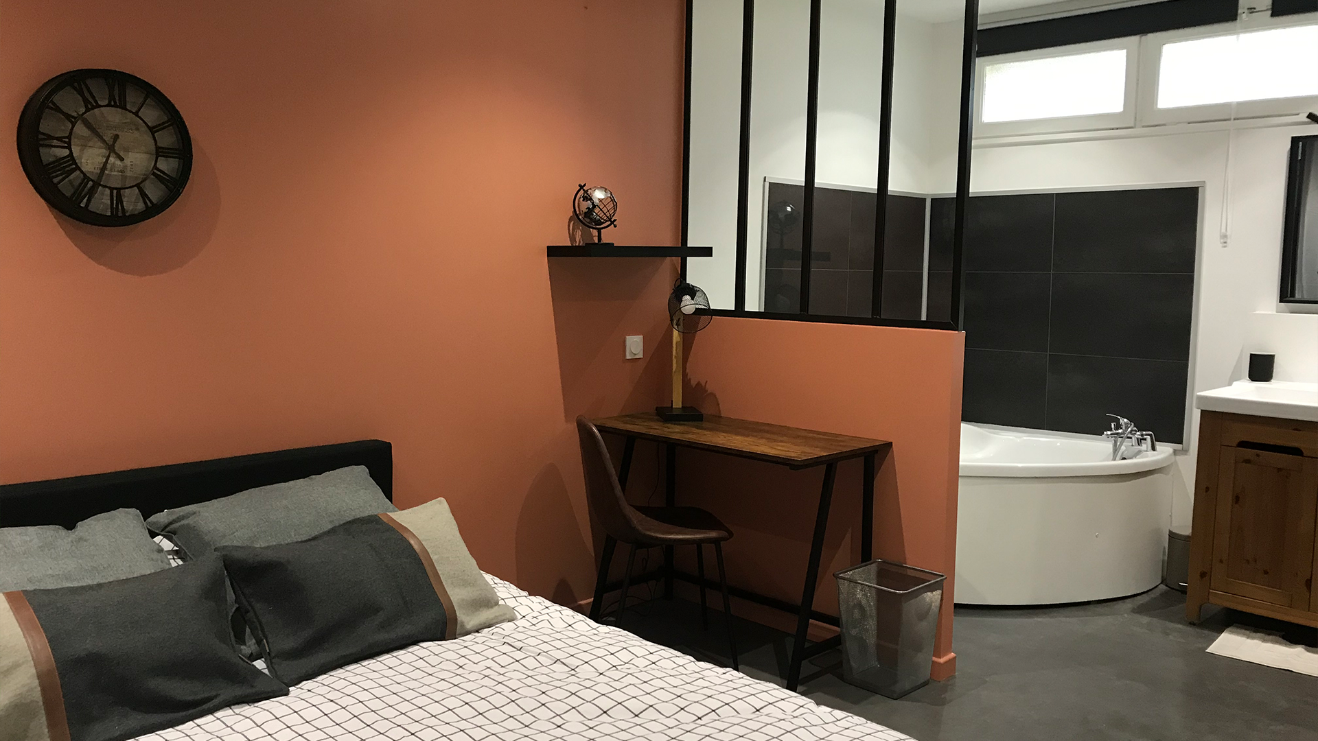 Chambre en colocation à Nantes avec mur terracotta, verrière noire, coin bureau en bois et salle de bain attenante moderne. Axirenov