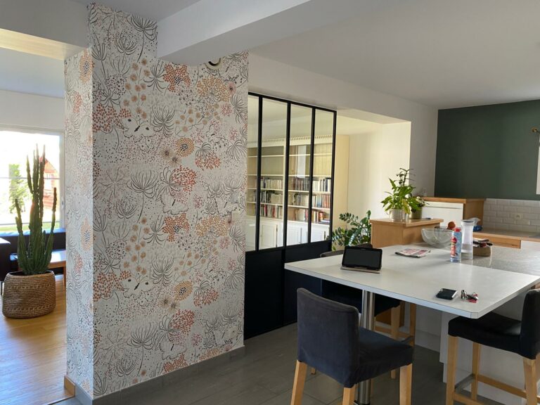 Mur décoré avec un papier peint floral, accompagnée d'une verrière noire et de murs aux teintes douces et élégantes, dans une cuisine ouverte contemporaine. axirenov