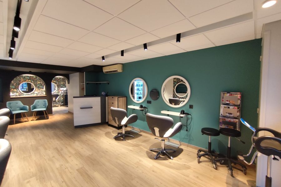 Intérieur d'un salon de coiffure rénové avec un revêtement de sol moderne et des murs peints en vert profond, créant une ambiance chaleureuse et élégante. à Treillières