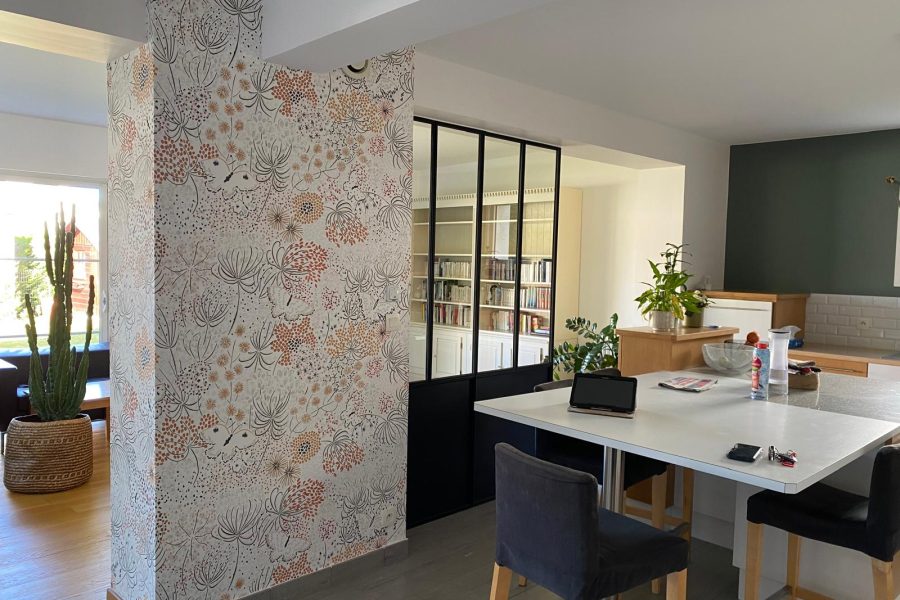 Mur décoré avec un papier peint floral, accompagnée d'une verrière noire et de murs aux teintes douces et élégantes, dans une cuisine ouverte contemporaine. axirenov